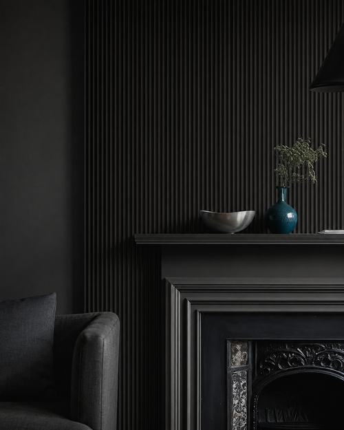 Dark room with black wall panelling, fireplace, and decorative items.