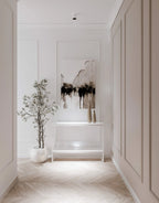 Modern panelled hallway with abstract art, a plant, and a white console table.