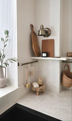 Nestled corner of a room with fluted panelled wall recess and shelves holding wooden boards, a candle, and decorative items.