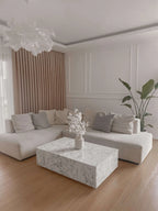 Modern living room with a white sectional sofa, marble coffee table, and decorative elements.
