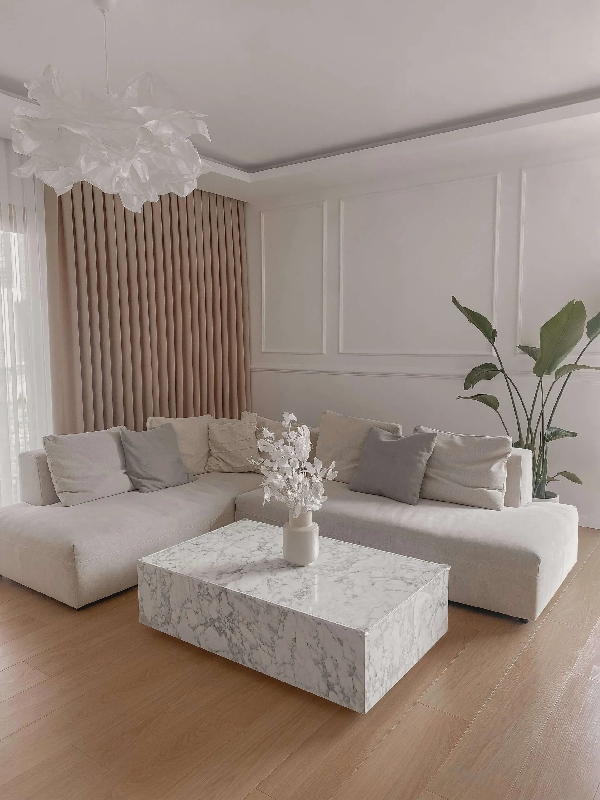 Modern living room with a white sectional sofa, marble coffee table, and decorative elements.