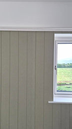 Window with white frame on a gray tongue and groove paneled wall