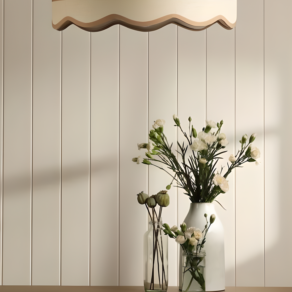 Decorative pendant light fixture with wavy design above a vase of flowers against a tongue and groove wood panelling