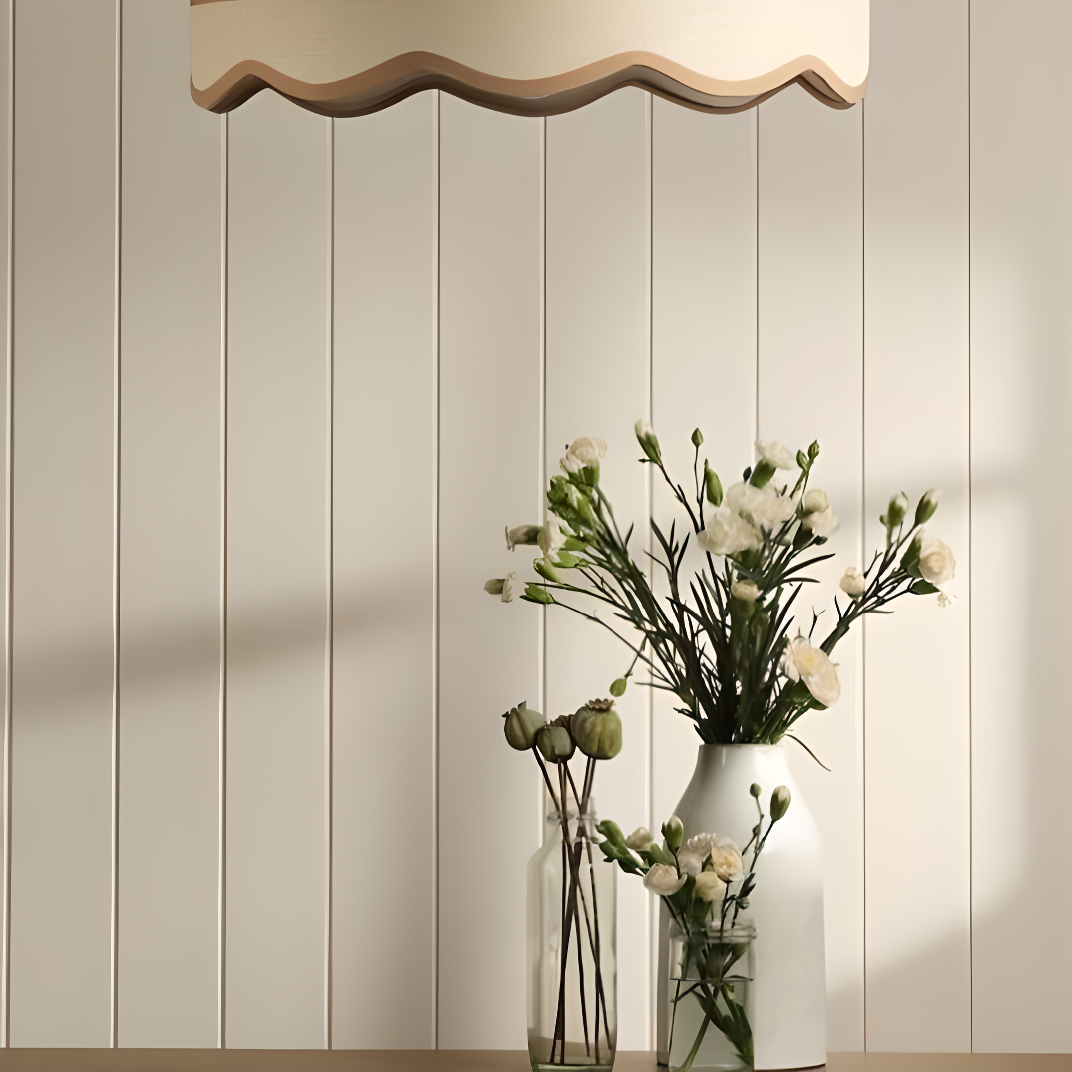 Decorative pendant light fixture with wavy design above a vase of flowers against a tongue and groove wood panelling