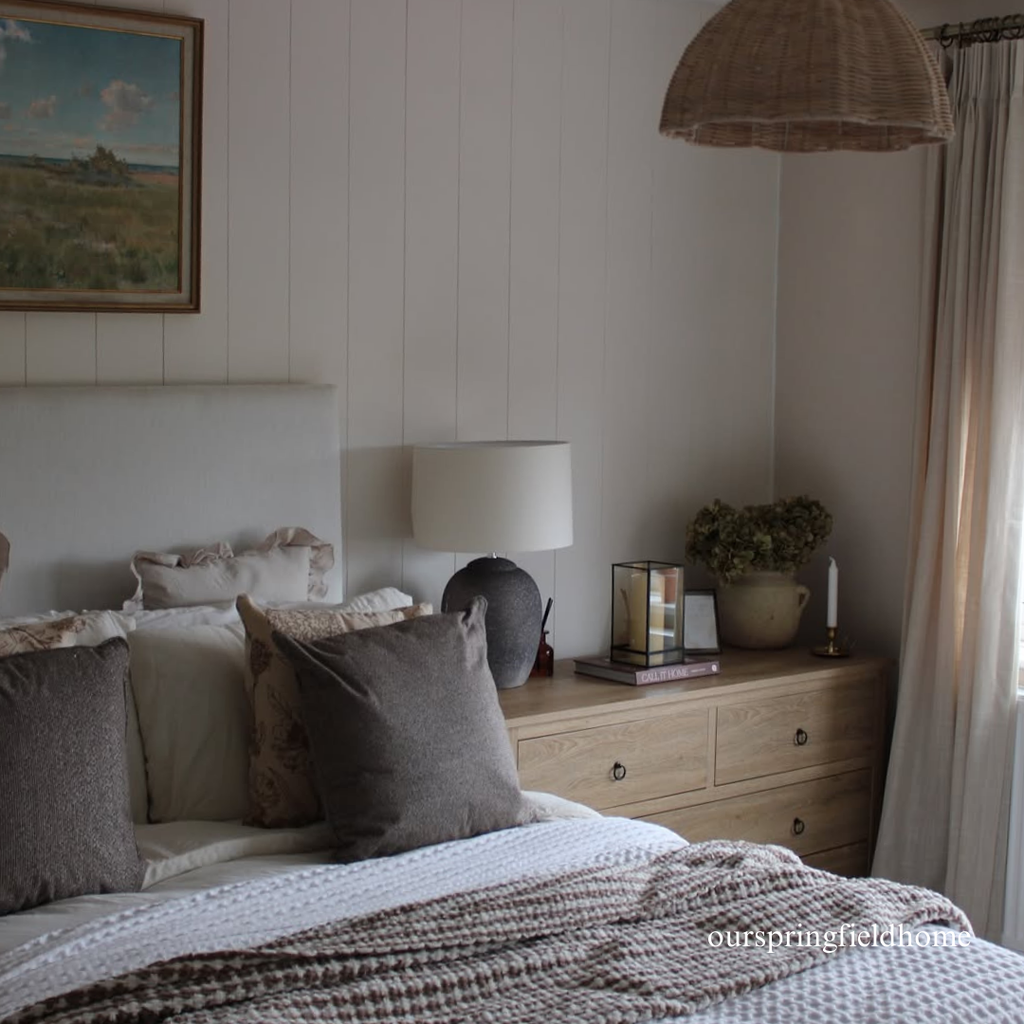 Cozy wall panelled bedroom with a bed, lamp, and dresser.
