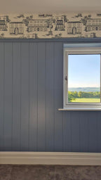 Wall with blue paneling, white window sill, and view of green landscape outside.