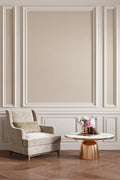 Elegant armchair with a small round table against a wall with decorative molding