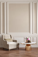 Elegant armchair with a small round table against a wall with decorative molding