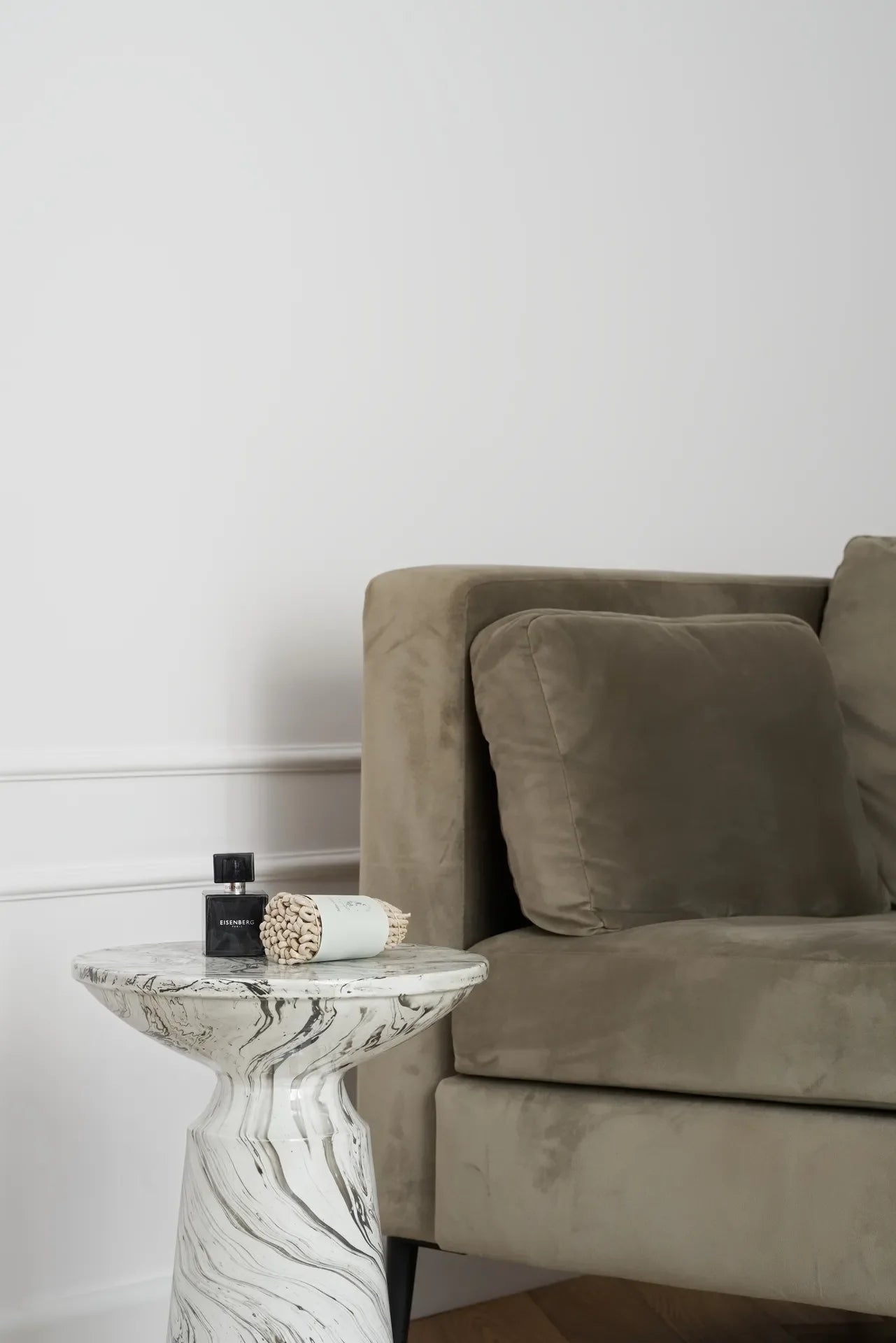 Gray sofa with a marble side table and decorative items against white wall panelling.